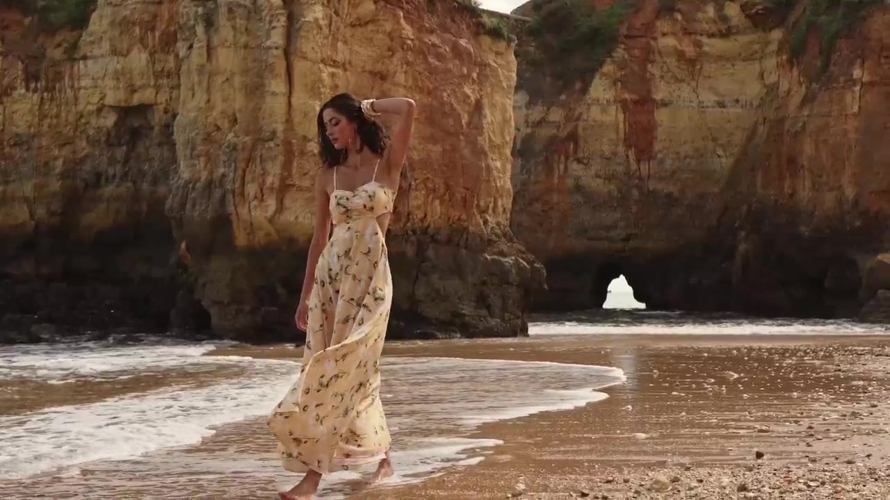 A woman in a light dress walking along the shore