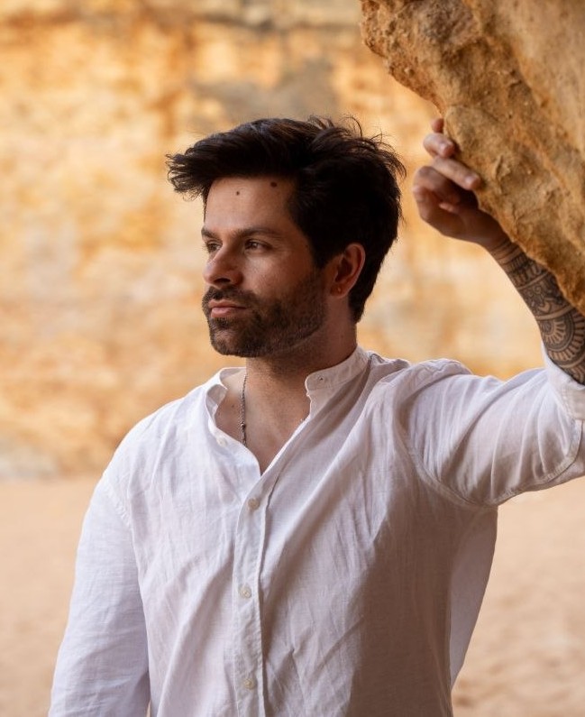 Tomas Muellerleily in a white shirt beside a rock